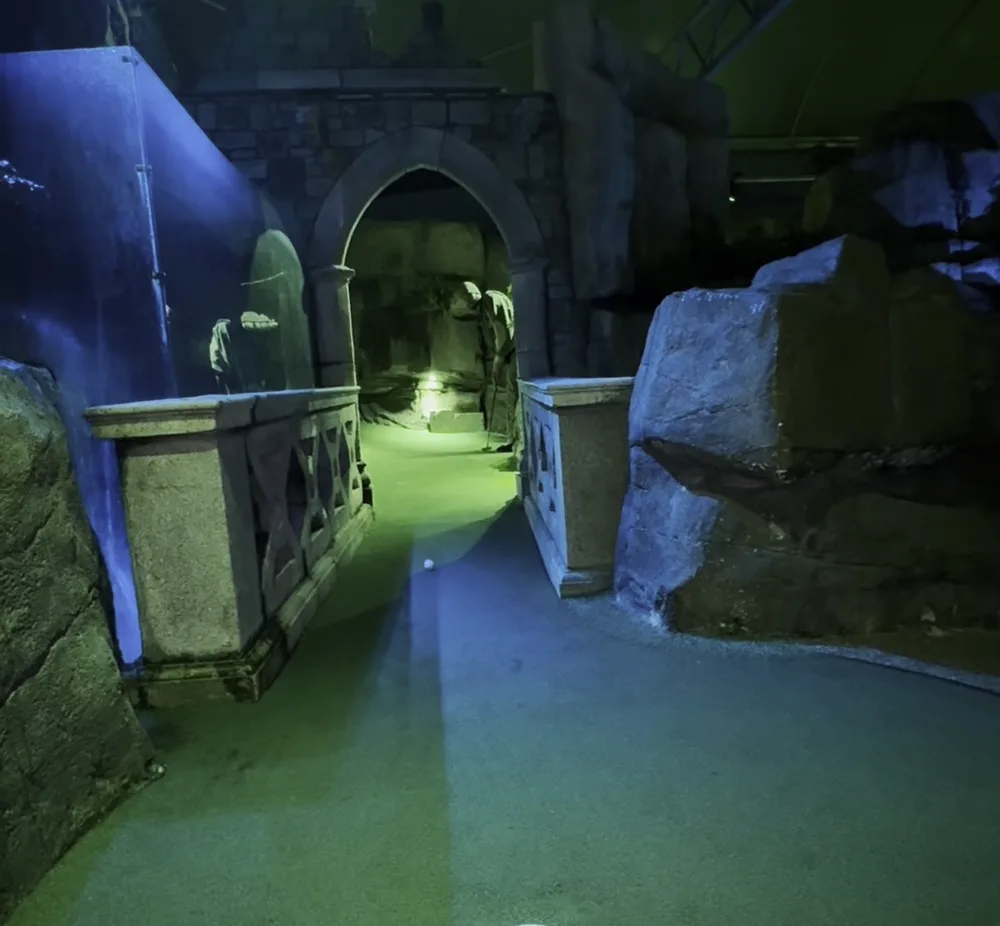 Stone ruins and arches lit in blue on a themed adventure golf hole
