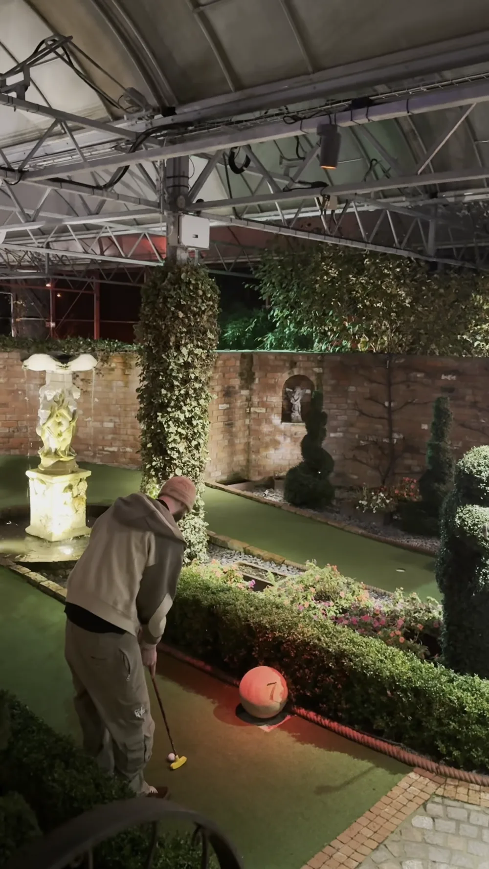 A player lining up a putt on a garden-themed adventure golf hole