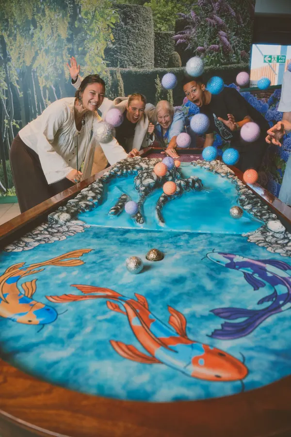 A group leaning in over the koi-pond hole