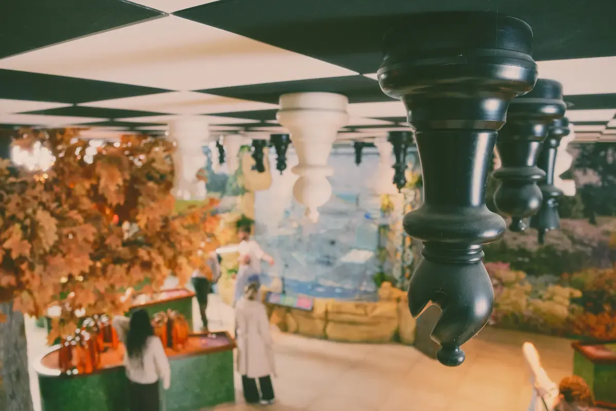 Giant chess pieces hanging upside-down from a checkerboard ceiling