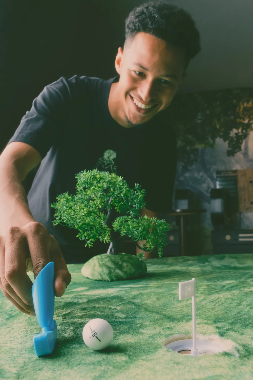 A player grinning as he lines up a Finga Golf putt