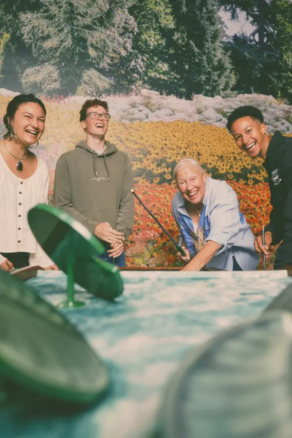 Four friends laughing across the Cue Golf lily-pad hole