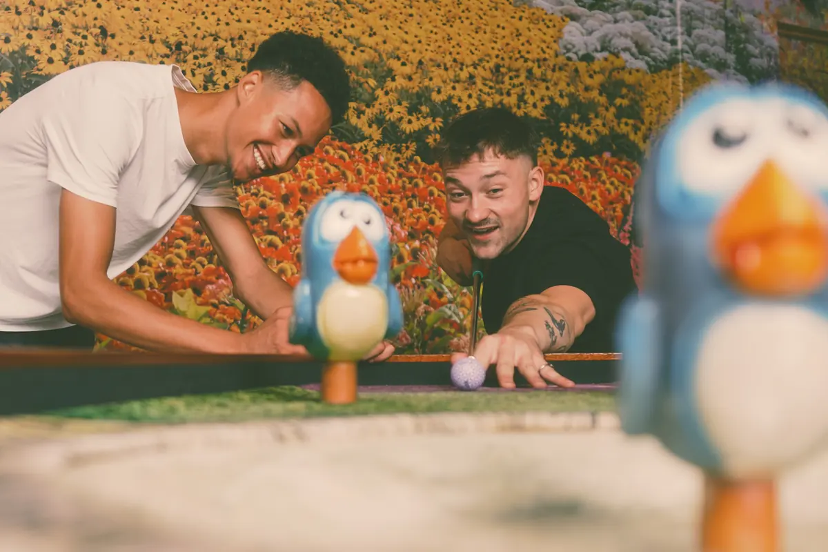 Two players lining up a shot past a model bird